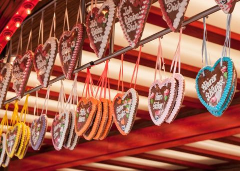 Eine bunte Auswahl an Lebkuchenherzen hängt an einem Marktstand. Jedes Herz hat eine liebevolle Botschaft und ist mit buntem Zuckerguss verziert.