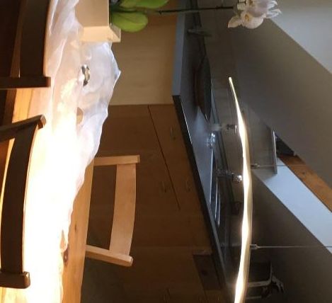 Ein moderner Essbereich mit einem Holztisch und Stühlen. Auf dem Tisch steht eine Orchidee und die Umgebung ist hell und einladend.