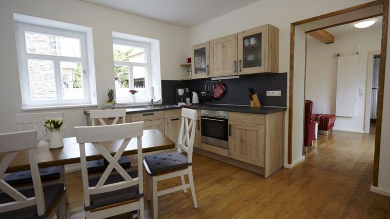 Une cuisine moderne avec des meubles en bois et des murs clairs. L'espace salle à manger est confortable et bien éclairé.