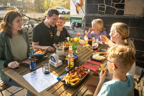 Eine Familie isst gemeinsam am Tisch am Alten Bahnhof in Ochtendung