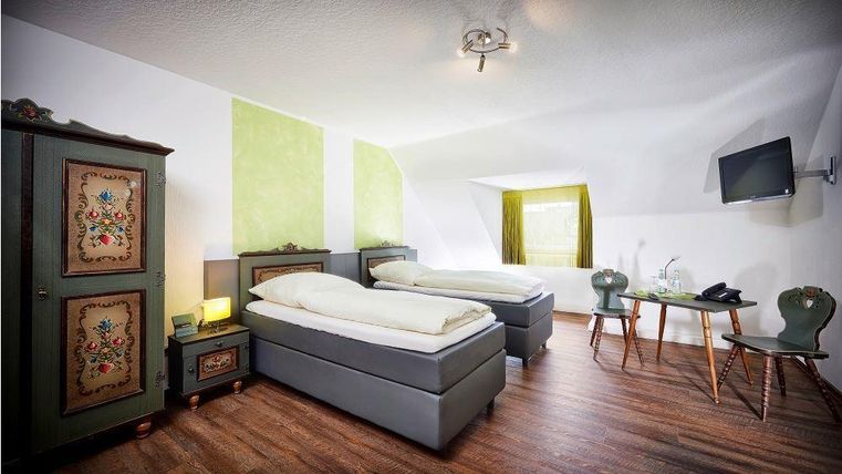 Ein gemütliches Schlafzimmer mit zwei Einzelbetten und einem Holzschrank. Der Raum hat eine freundliche Atmosphäre mit hellen Wänden und einem großen Fenster.