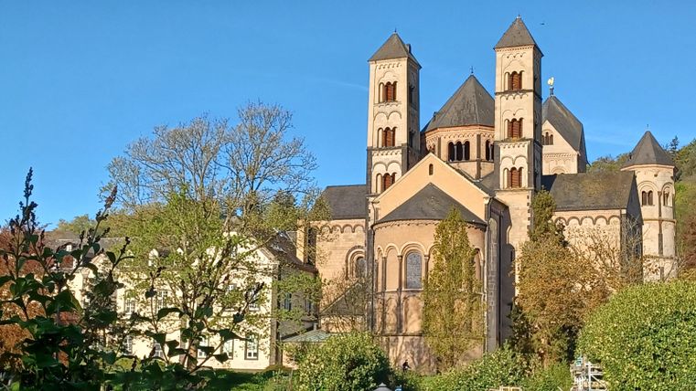 Eine beeindruckende Kirche mit hohen Türmen und schöner Architektur. Umgeben von Bäumen und einem klaren blauen Himmel.