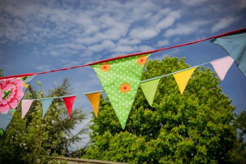 Bunte Wimpel hängen über einem grünen Garten. Der Himmel ist mit einigen Wolken bedeckt.