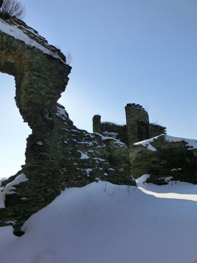 Ruines d'un ancien bâtiment, entourées de neige. Le ciel est clair et bleu.