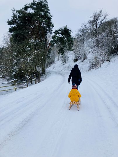 Ein Kind wird auf einem Schlitten durch die Winterlandschaft gezogen