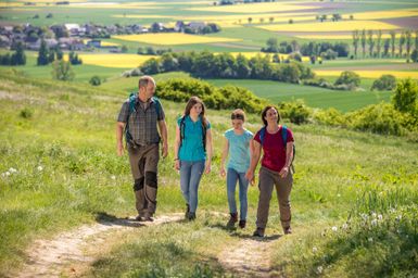 Wanderer laufen über den Paradiesweg im Frühling, der Raps blüht