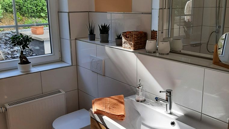 Une salle de bain moderne avec un sol en carrelage clair et des armoires en bois.
La lumière naturelle entre par la fenêtre et crée une atmosphère chaleureuse.
