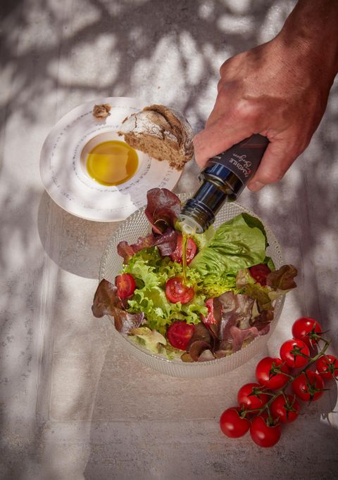 Ein frischer Salat mit verschiedenen Blattsalaten und Kirschtomaten. Im Hintergrund sind ein Stück Brot und ein rohes Ei zu sehen.