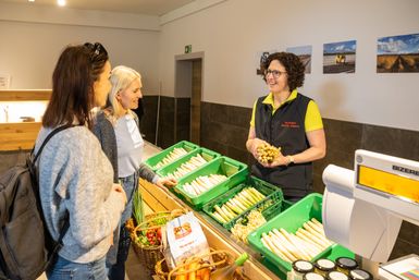 Zwei Damen werden im Hofladen Adams zu frischem Spargel beraten.