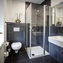 Ein modernes Bad mit einer glaswändigen Dusche und eleganten Fliesen. Die Einrichtung umfasst ein Waschbecken und eine Toilette.