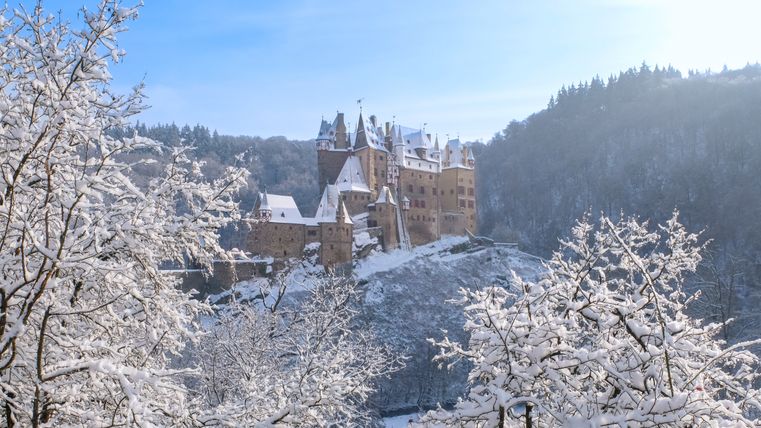Burg Eltz ist umgeben von Wald, es ist alles schneebedeckt. 