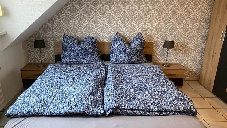 Ein gemütliches Schlafzimmer mit einem Doppelbett und Blumenbettwäsche. Neben dem Bett stehen zwei Nachttische mit Lampen.