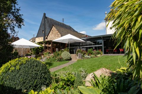 Ein gemütliches Haus mit einem großen Garten. Der Außenbereich ist mit Sonnenschirmen und grünen Pflanzen dekoriert.