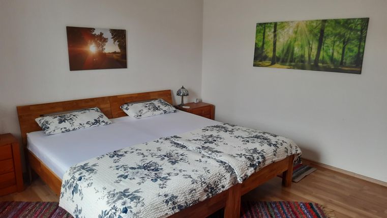 Ein gemütliches Schlafzimmer mit einem großen Doppelbett und einer schönen Bettdecke. An den Wänden hängen Bilder von Natur.