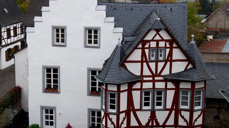 Ein historisches Gebäude mit weißem Putz und sichtbaren Fachwerk-Elementen. Die Architektur zeigt eine interessante Kombination aus verschiedenen Stilen.