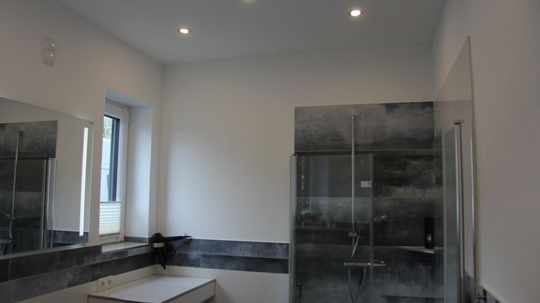 Une salle de bains moderne avec une douche et un lavabo. Les murs sont peints dans des couleurs neutres et il y a beaucoup de lumière naturelle.