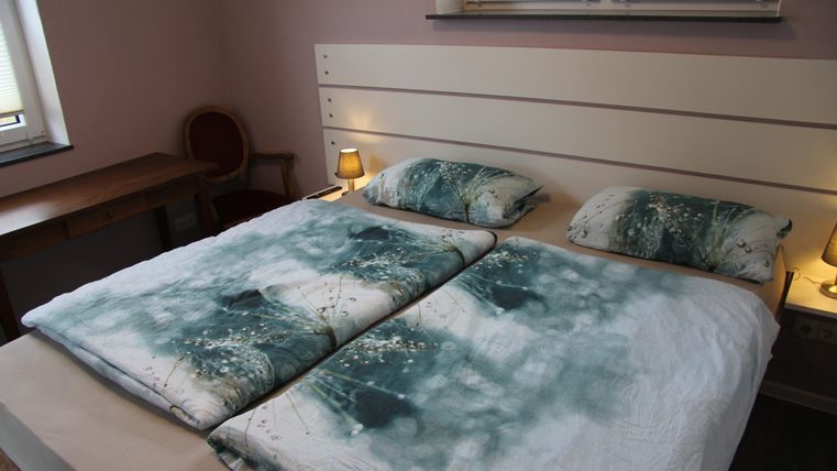 Une chambre confortable avec un grand lit et des couvre-lits décoratifs. Les murs sont peints dans des couleurs douces et il y a une petite table ainsi qu'un coin salon.