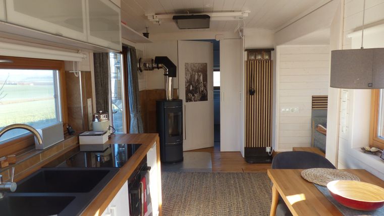 Eine moderne Küche mit einem offenen Wohnbereich. Helle Wände und große Fenster sorgen für viel Tageslicht.