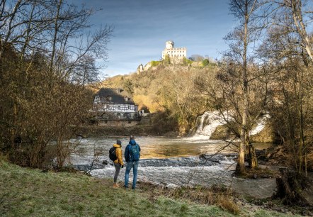 Zwei Personen am Elzbach, mit Blick auf die Pyrmonter Mühle und Burg Pyrmont. Herbstliche Landschaft mit Wasserfall und Fachwerkhaus., © Eifel Tourismus GmbH, D. Ketz