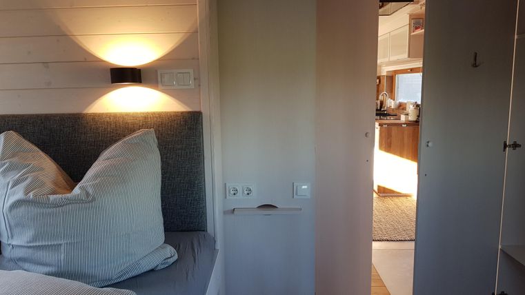 Ein gemütliches Schlafzimmer mit einem Doppelbett und sanfter Beleuchtung. Im Hintergrund ist die offene Küche sichtbar.