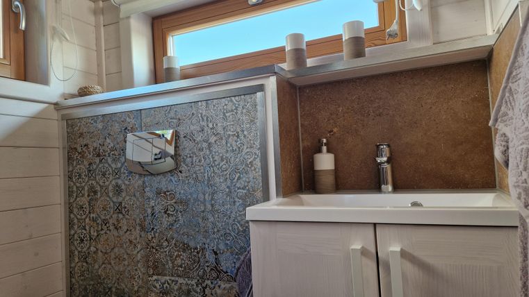 Ein modernes Badezimmer mit einer stilvollen Wandgestaltung und einem Waschbecken. Durch das Fenster strömt natürliches Licht herein.