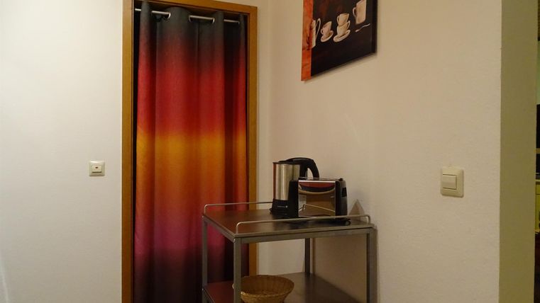 Ein gemütlicher Raum mit einem Farbverlauf-Vorhang und einem kleinen Tisch. Auf dem Tisch stehen eine Kaffeekanne und eine Schüssel.