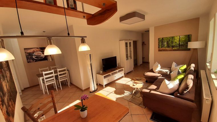 Un salon confortable avec une salle à manger et une grande fenêtre. Le mobilier est moderne et lumineux, avec des canapés confortables et une table à manger.