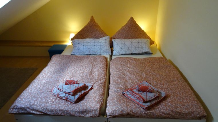 Ein gemütliches Schlafzimmer mit zwei getrennten Betten und hellen Bettdecken. Sanftes Licht schafft eine einladende Atmosphäre.