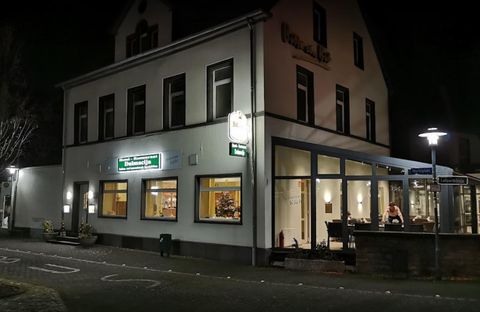 Ein Restaurantgebäude bei Nacht, beleuchtet von warmem Licht. Die Fenster zeigen eine einladende Atmosphäre mit Gästen drinnen.