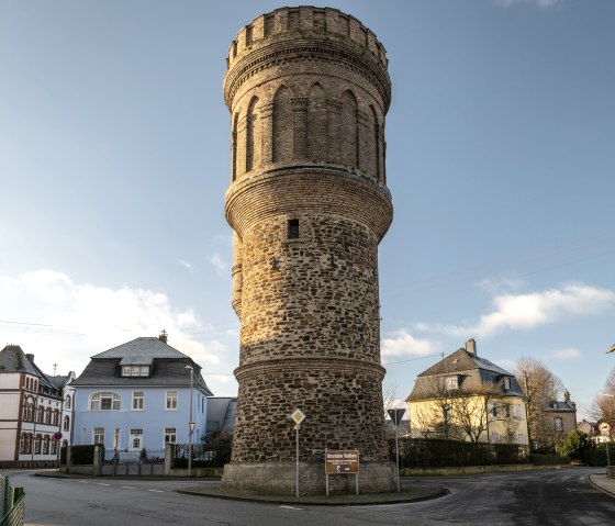 Ein historischer Wasserturm aus Stein in Münstermaifeld, umgeben von Wohnhäusern, bei klarem Himmel und Sonnenschein., © Eifel Tourismus GmbH, D. Ketz