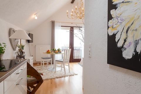 Eine helle und einladende Wohnung mit einem Essbereich und einem schönen Blick auf den Balkon. Kunstwerke und Pflanzen verleihen dem Raum eine gemütliche Atmosphäre.