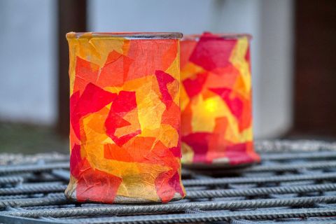Zwei bunt gestaltete Laternen aus transparentem Material strahlen warmes Licht aus. Die Farben umfassen Rot, Orange und Gelb und sorgen für eine gemütliche Atmosphäre.