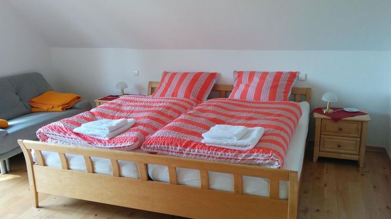 Ein gemütliches Schlafzimmer mit zwei Betten und gestreiften Bettwäsche. Es gibt einen Nachttisch und ein Sofa in der Ecke.