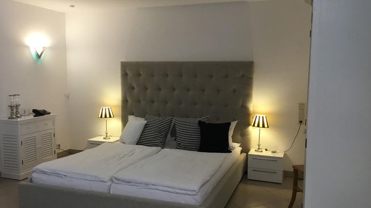 Ein modernes Schlafzimmer mit einem großen, gepolsterten Bett und Nachttischen. Sanfte Beleuchtung schafft eine gemütliche Atmosphäre.