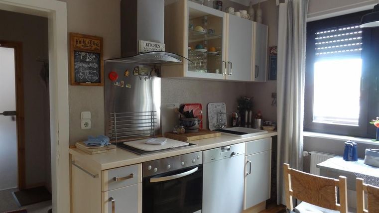 Eine helle und moderne Küche mit weißen Schränken und einem Herd. Der Essbereich ist gemütlich gestaltet mit einem Tisch und Stühlen.