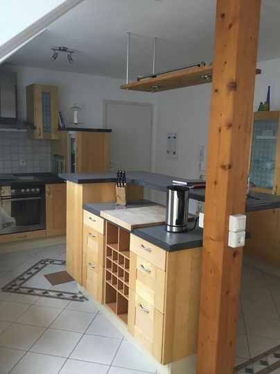 Eine moderne Küche mit Holz- und Granitoberflächen. Sie verfügt über einen großen Küchenblock und ausreichend Stauraum.