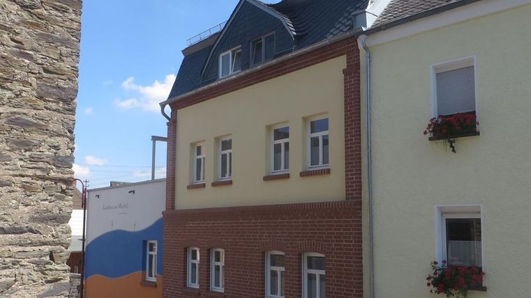 Un bâtiment moderne avec une façade jaune et rouge dans une rue calme. À l'arrière-plan, on voit une peinture murale bleue.