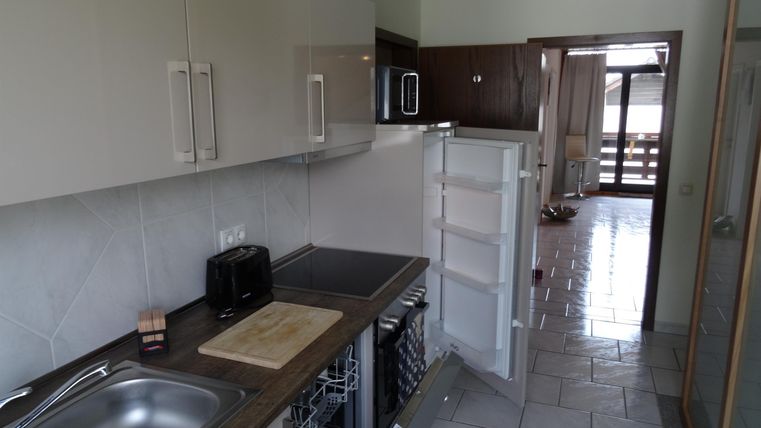 Eine moderne Küche mit einer Spüle und einem Kühlschrank. Der Raum hat helle Wände und fliesenböden.